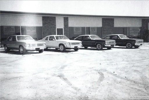 Black and white photo of classic cars parked outside the original dealership