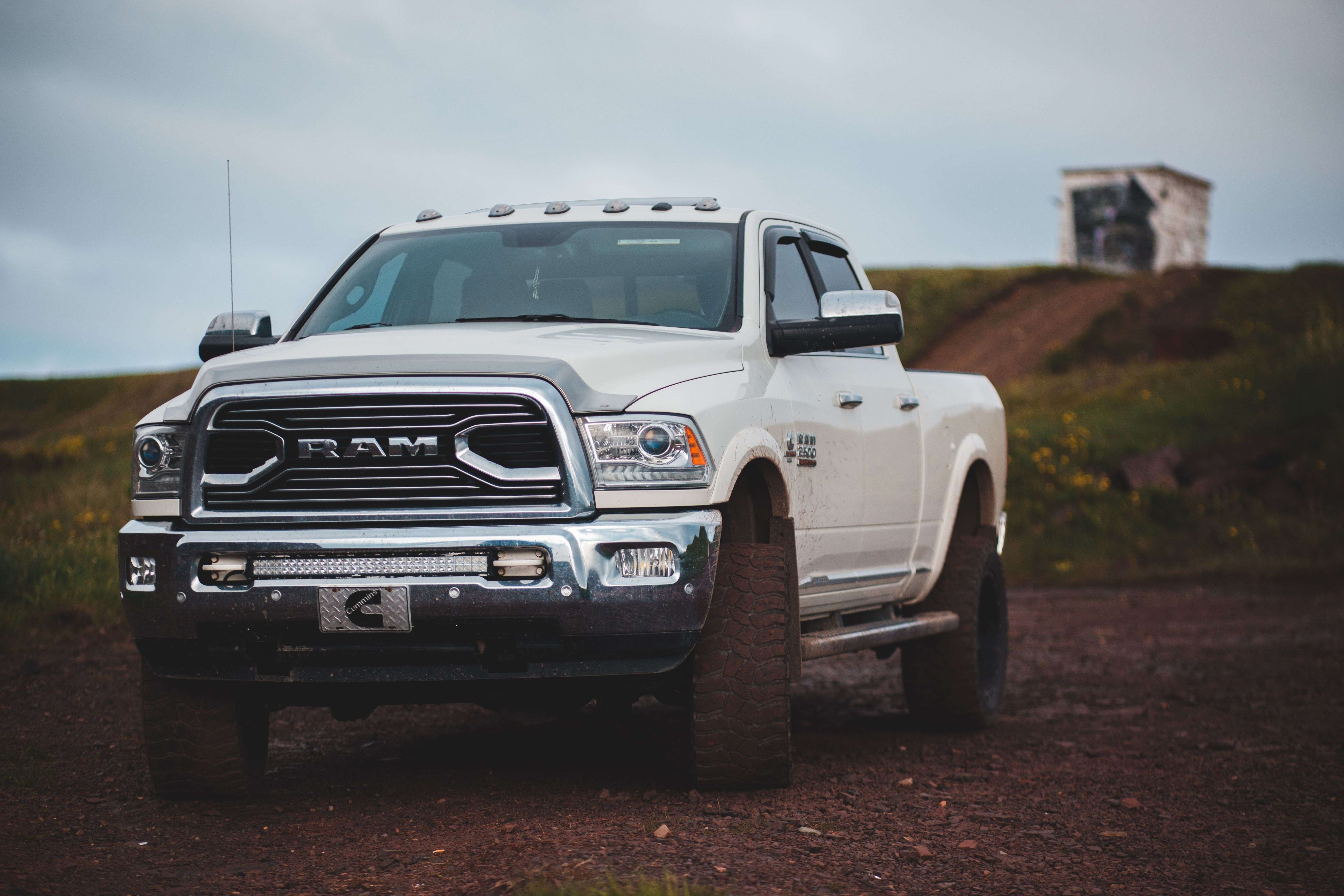 A white RAM truck parked on a road with a blurry country background.