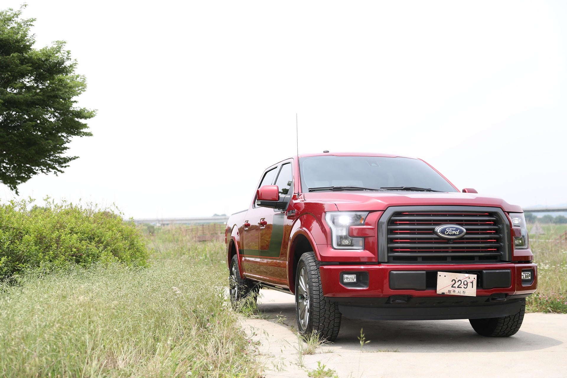 A red Ford F-150 truck, one of the most reliable trucks in the United States, on a country road.