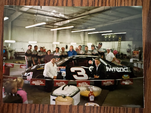 Vern Laures and the dealership team gathered around a No. 3 race car in the shop